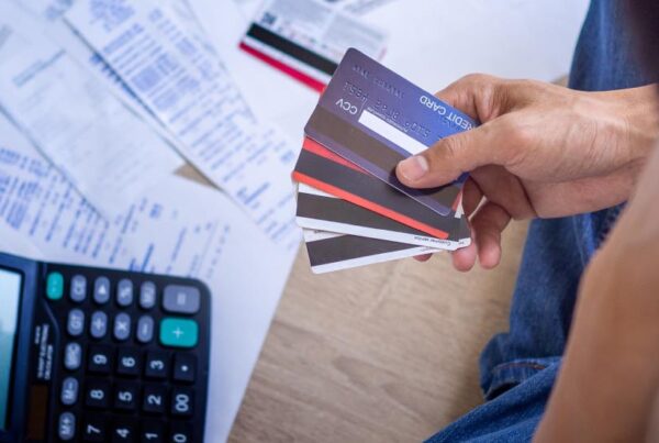 man-holding-credit-cards-with-calculator-and-bill-statements-in-background