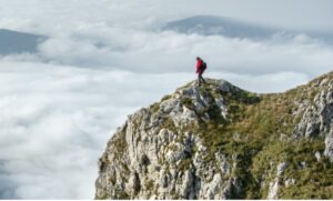 man-on-mountain-side-looking-over-valley-below